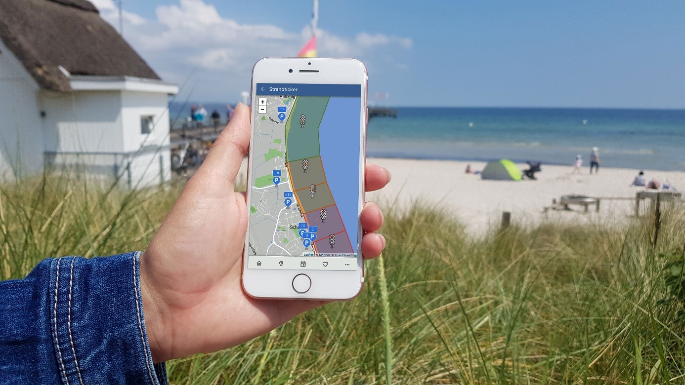 Der Strandticker auf einem Smartphone mit Strand im Hintergrund
